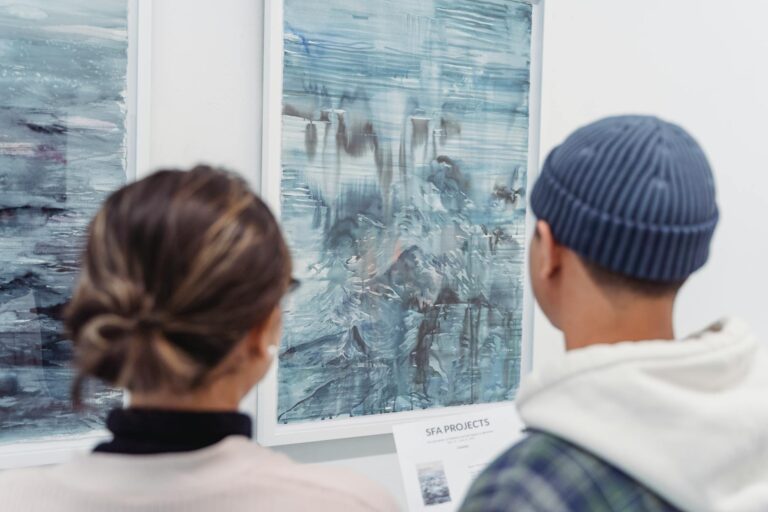 man and woman standing near the abstract paintings hanged on the wall